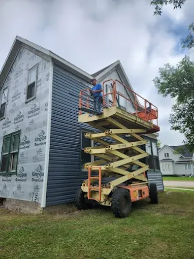 Crew installing new siding on a home from a lift